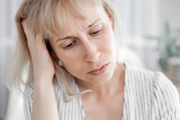 Una mujer con dolor de cabeza se sienta en una silla en la sala de estar Terapia psicológica sin energía falta de sueño