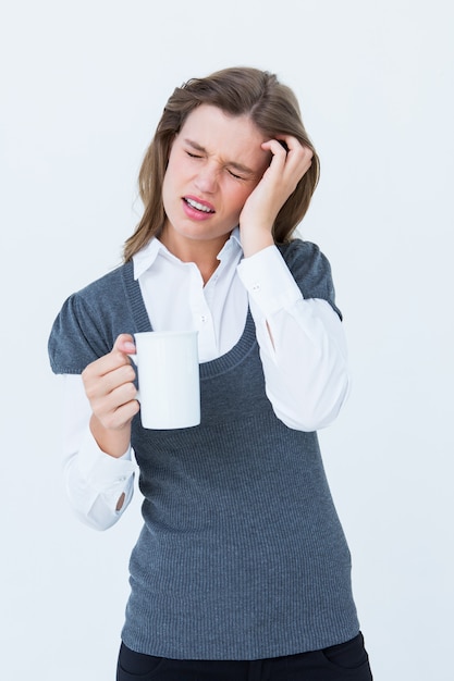 Mujer con dolor de cabeza sosteniendo la taza sobre fondo blanco