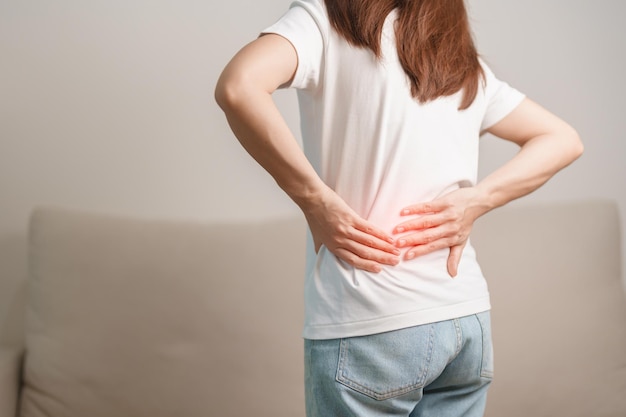 mujer con dolor de espalda mientras se sienta en el sofá en casa mujer adulta con concepto muscular