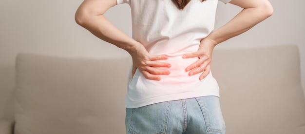 mujer con dolor de espalda mientras se sienta en el sofá en casa mujer adulta con músculo t