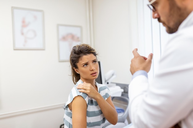 Foto mujer con dolor de hombro doctor trabajando en la oficina y escuchando al paciente, ella está explicando sus síntomas concepto de atención médica y asistencia