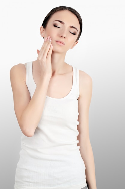 Mujer en dolor. primer plano de hermosa mujer joven sensación dolorosa dolor de muelas, tocando la cara con la mano. triste niña estresada sintiendo fuertes dientes, mandíbula o dolor de cuello. salud y cuidado dental.