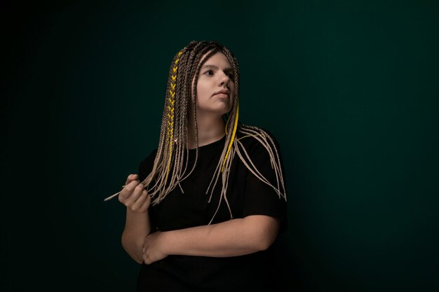 Mujer con dreadlocks frente a la pared verde