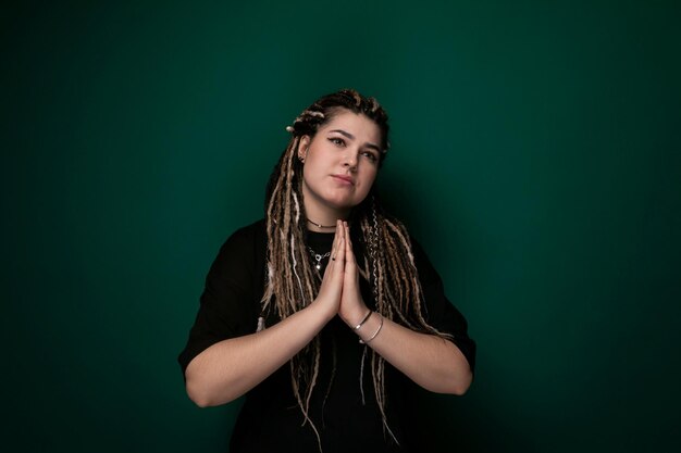 Mujer con dreadlocks de pie frente a la pared verde