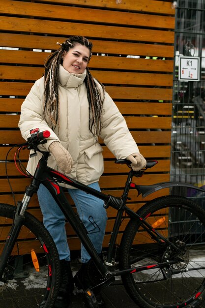 Mujer con dreadlocks de pie junto a la bicicleta