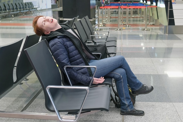 Mujer duerme con la boca abierta en la zona de salida de un aeropuerto internacional