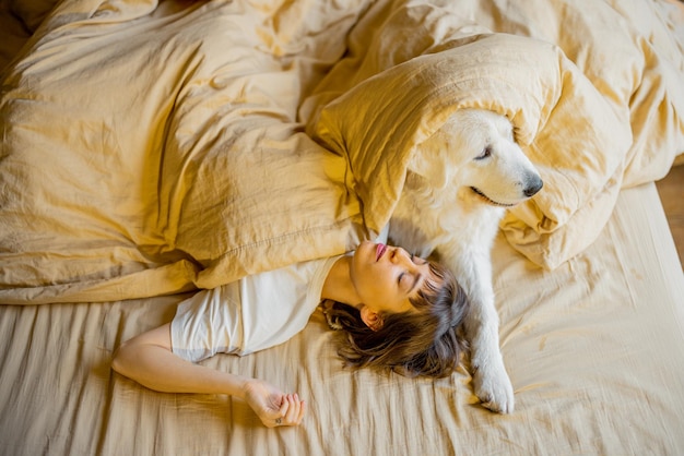 Mujer duerme con su lindo perro en la cama