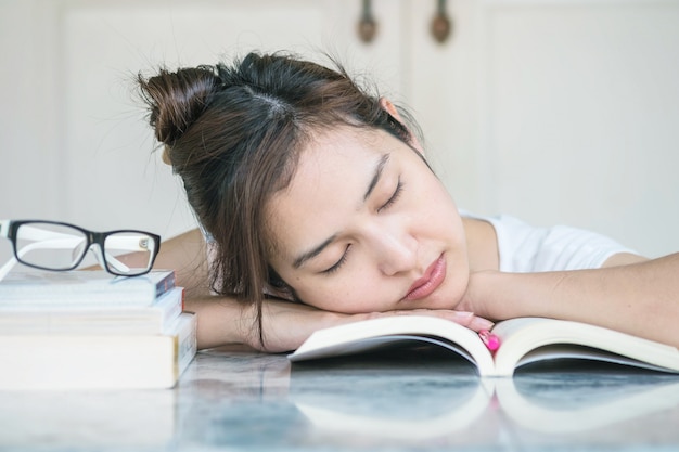 Mujer durmiendo después de que ella se cansara de leer con un libro sobre mesa de mármol
