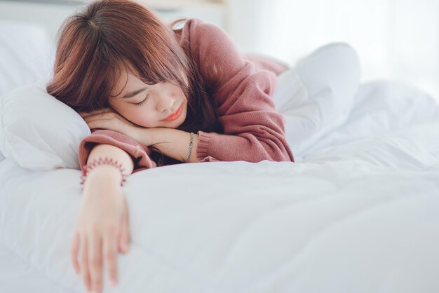 Mujer durmiendo, joven y hermosa mujer asiática durmiendo en una cama blanca