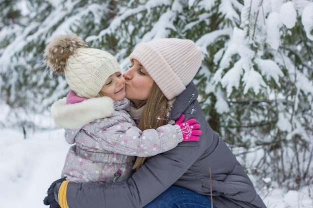 mujer e hija pequeña se abrazan en snowy fotest