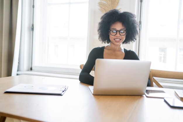 Mujer economista independiente usa una computadora portátil en el espacio de coworking de la oficina chat de video con un colega