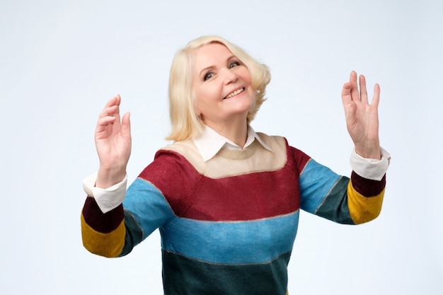 Mujer de edad alegre en suéter de color bailando.