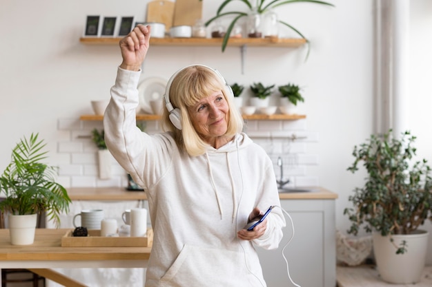 Mujer de edad avanzada en casa disfrutando de la música en auriculares