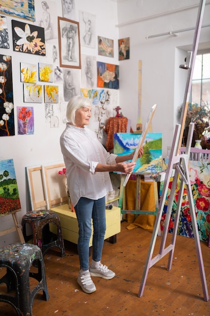 Mujer de edad con estilo. Elegante mujer de edad con jeans y zapatillas de deporte pintura amorosa mirando la imagen