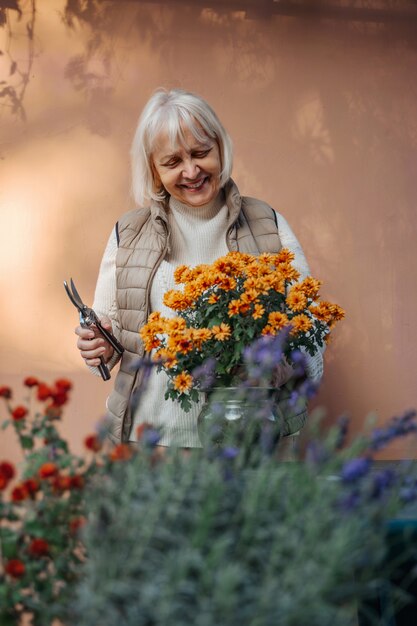 Mujer de edad feliz trabajando con flores en el jardín. Pensionista senior positiva