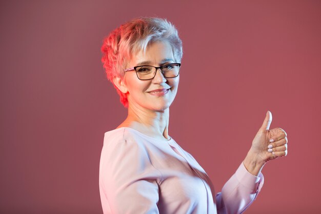 mujer de edad, con gafas con un peinado corto con un gesto de la mano