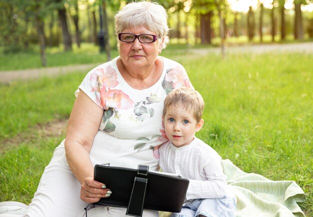 Mujer de edad sonriente con nieto divertido relajarse en la naturaleza.