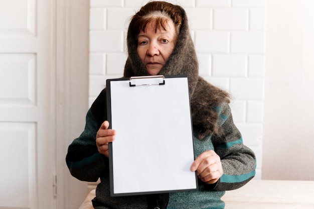 Mujer de edad con tablero publicitario en blanco