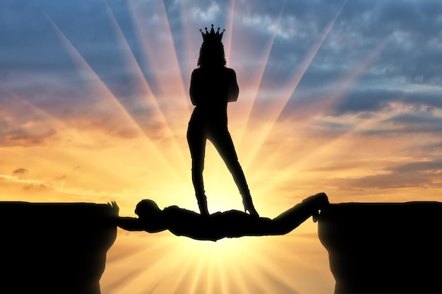 Mujer egoísta con una corona de pie sobre un hombre en forma de puente sobre un abismo. Concepto de egoísmo e interés personal