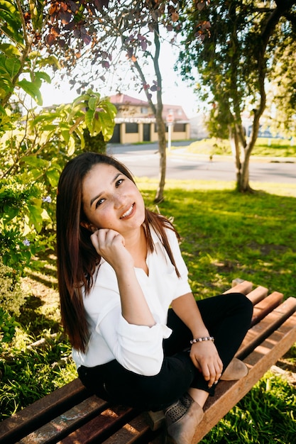 Foto mujer ejecutiva con su teléfono en un banco del parque