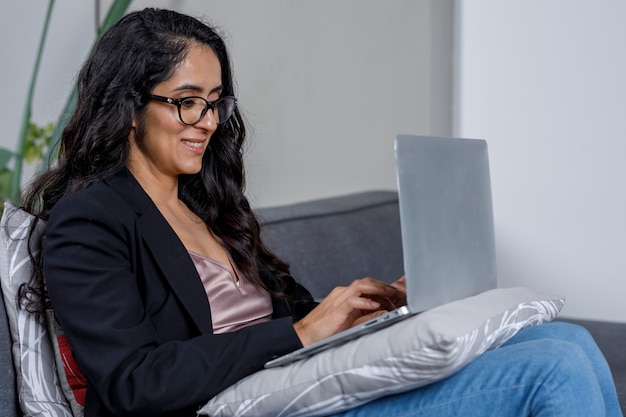 Mujer ejecutiva trabalhando desde a sala de sua casa em um portatil ordenador para a nova normalidade