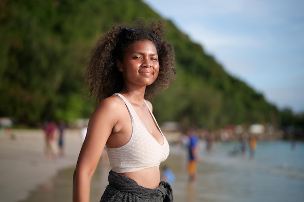 Mujer ejercita y estira los músculos antes de hacer ejercicio al aire libre Retrato sexy dama africana asiática preparándose para hacer ejercicio en la playa