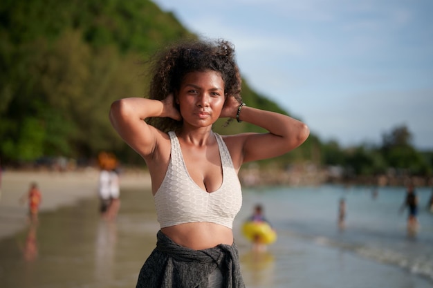 Mujer ejercita y estira los músculos antes de hacer ejercicio al aire libre Retrato sexy dama africana asiática preparándose para hacer ejercicio en la playa