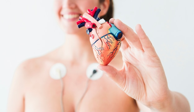 Mujer con electrodos sosteniendo figurita de corazon