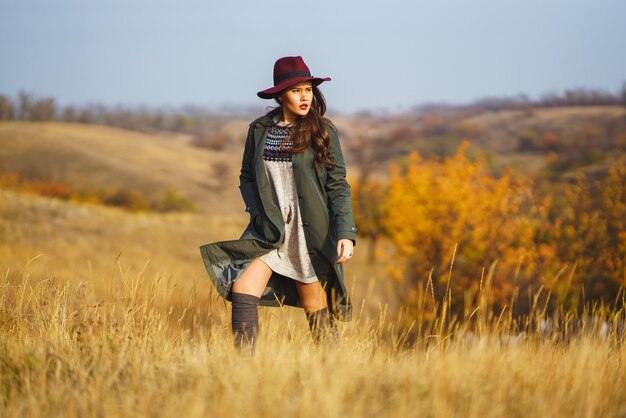 Mujer elegante con un abrigo en el parque de otoño