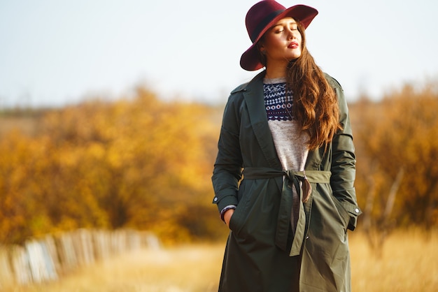 Mujer elegante con un abrigo en el parque de otoño