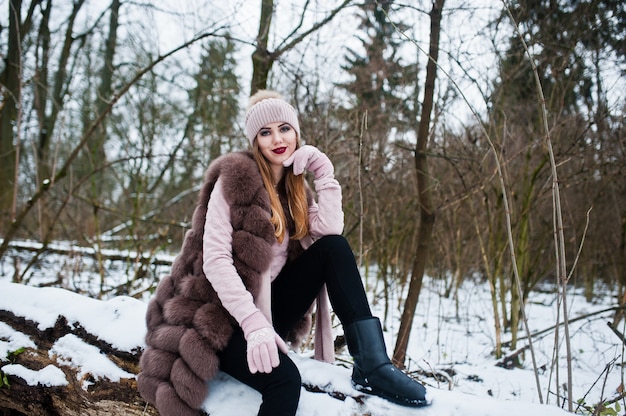 Mujer elegante abrigo de piel y sombreros en el bosque de invierno.