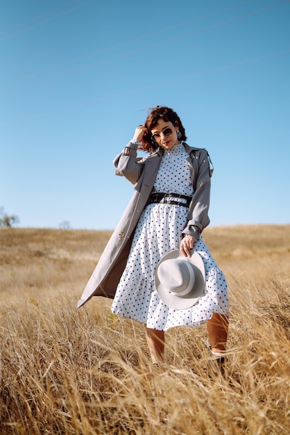 Mujer elegante con abrigo y sombrero disfruta de la naturaleza otoñal Mujer joven camina en el parque