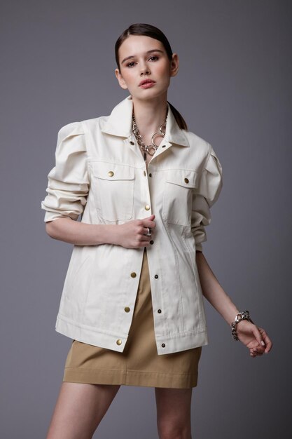 Mujer elegante en accesorios de falda de arena beige bastante camisa blanca sobre fondo gris Foto de estudio