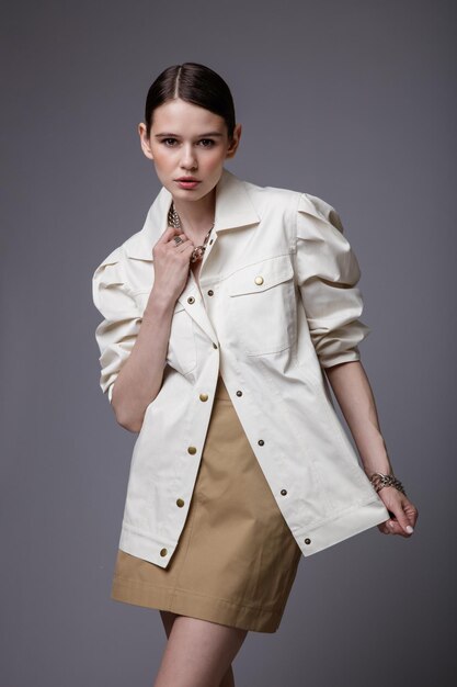 Mujer elegante en accesorios de falda de arena beige bastante camisa blanca sobre fondo gris Foto de estudio