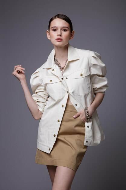 Mujer elegante en accesorios de falda de arena beige bastante camisa blanca sobre fondo gris Foto de estudio