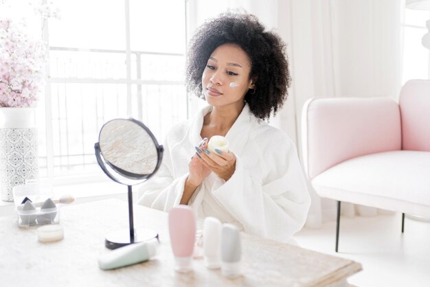 Mujer elegante aplicando cuidado de la piel en una habitación luminosa y aireada encarnando el cuidado personal y los rituales de belleza con elegancia