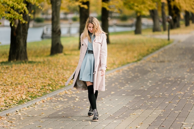 Mujer elegante atractiva con sombrero en un abrigo camina en el parque de otoño. Otoño retrato de una niña. Concepto de temporada de otoño.