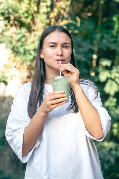 Foto mujer elegante bebiendo matcha latte en el parque