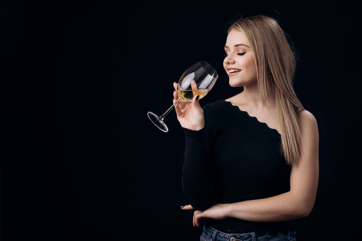 Mujer elegante bebiendo vino en un estudio