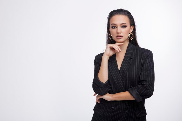 mujer elegante con bonita chaqueta negra, pantalones de cuero, botas de fondo blanco.