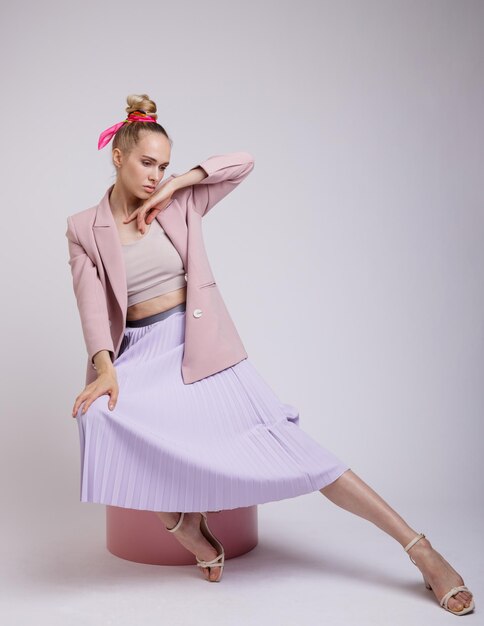 mujer elegante con una bonita chaqueta rosa pastel, falda lila con fondo blanco