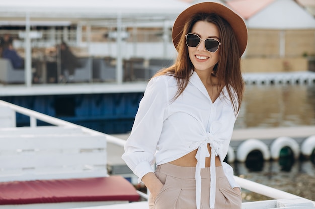 Una mujer elegante camina por la playa en un cálido día de verano en la puesta de sol