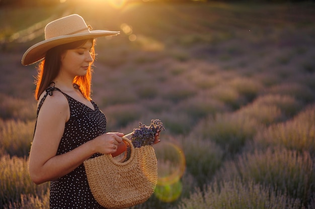 Mujer elegante en campo de lavanda con bolsa de mimbre