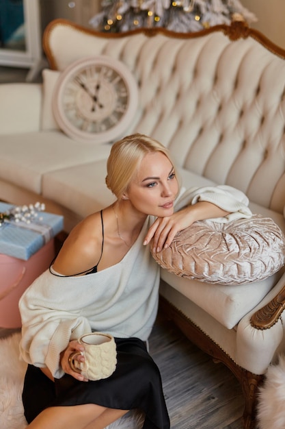 Mujer elegante en casa en el sofá con una taza de té