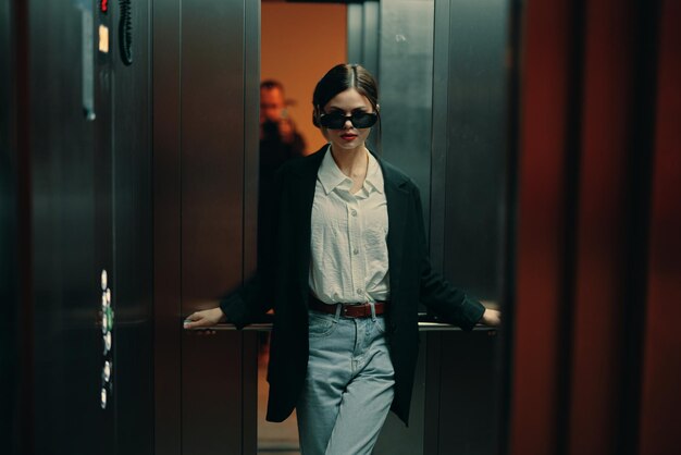 Foto mujer elegante en chaqueta negra y gafas de sol posando en ascensor modelo de moda luz cinematográfica oscura y color glamour vintage