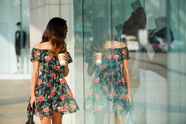 Foto mujer elegante con copa mirando escaparate