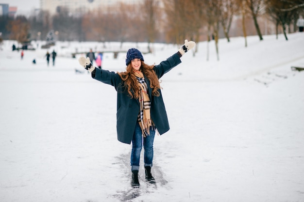 Mujer elegante divertida que monta la pista de hielo en parque del invierno.