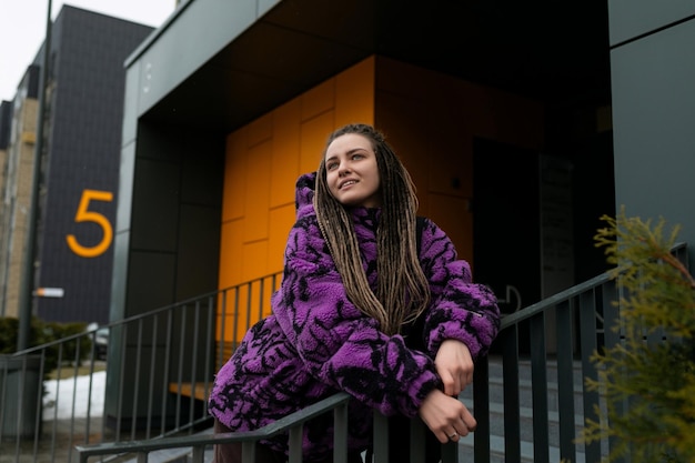 Mujer elegante e informal con dreadlocks que lleva un concepto de estilo de vida de chaqueta púrpura