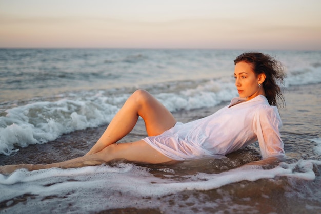 Mujer elegante en elegante vestido blanco posando cerca del mar tiempo de verano viaje fin de semana relajarse