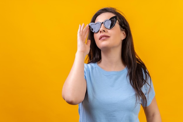 Mujer elegante con gafas de sol en forma de corazón mirando hacia arriba